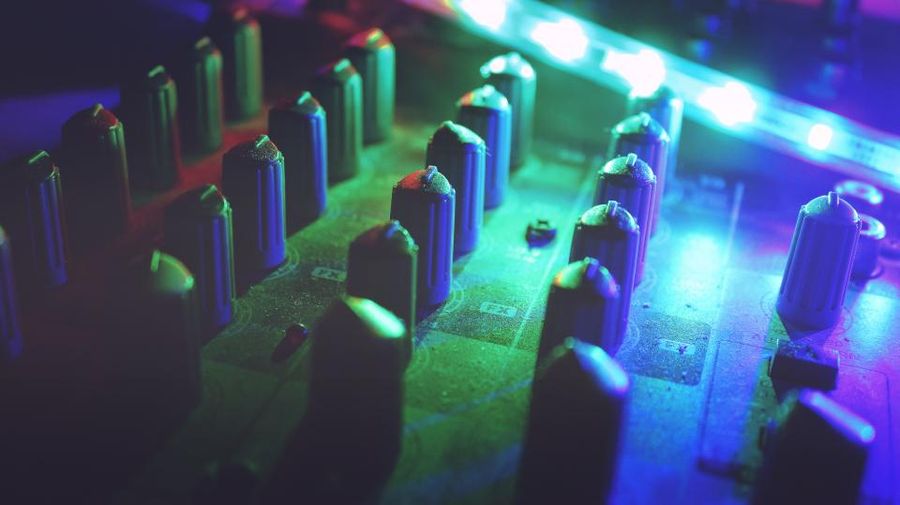 DJ mixer controls lit in coloured light